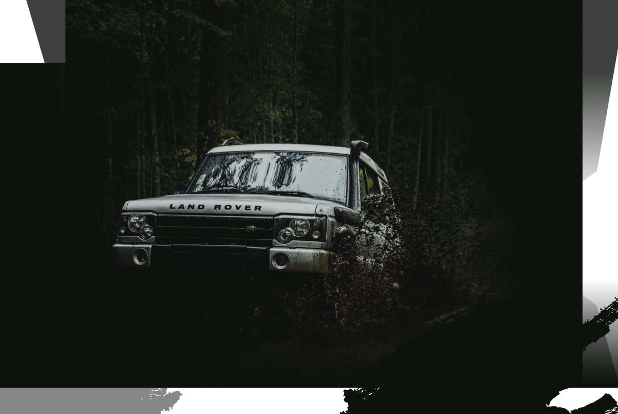 silver land rover driving through the mud in the forest